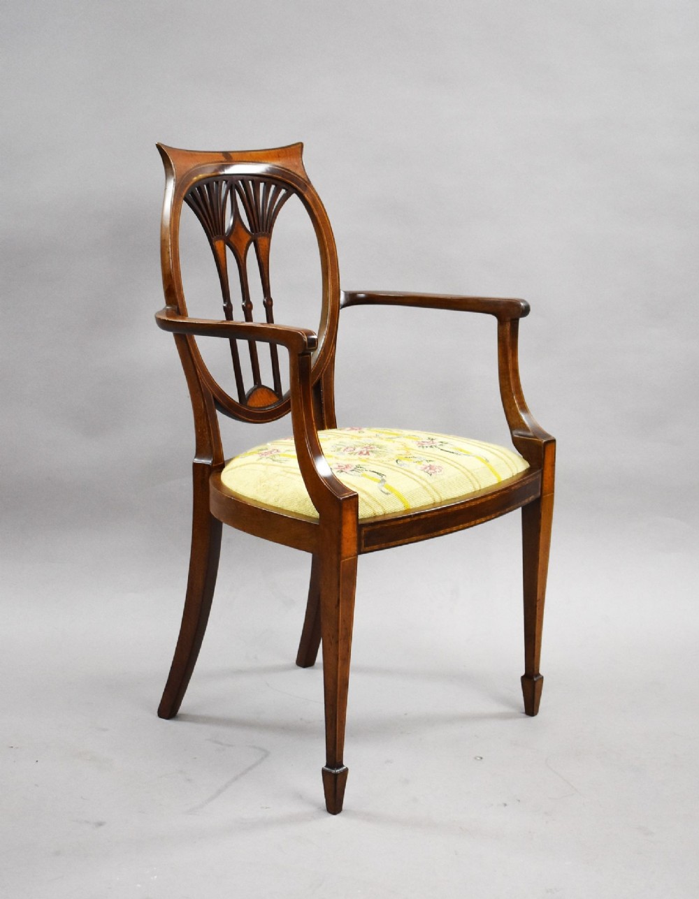 A pair of Edwardian Sheraton Revival mahogany armchairs featuring oval backs with vertical fan splats, swept arms, satinwood inlays, and yellow floral upholstered seats. View II