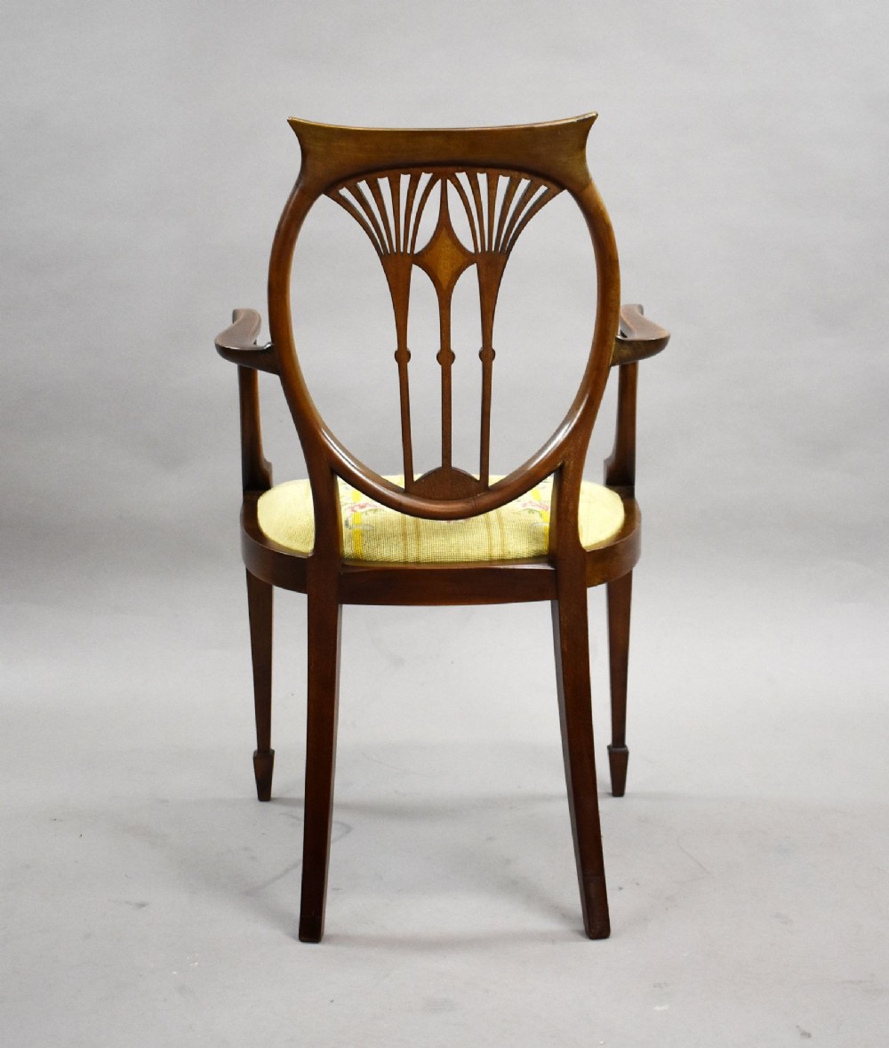 A pair of Edwardian Sheraton Revival mahogany armchairs featuring oval backs with vertical fan splats, swept arms, satinwood inlays, and yellow floral upholstered seats. View V