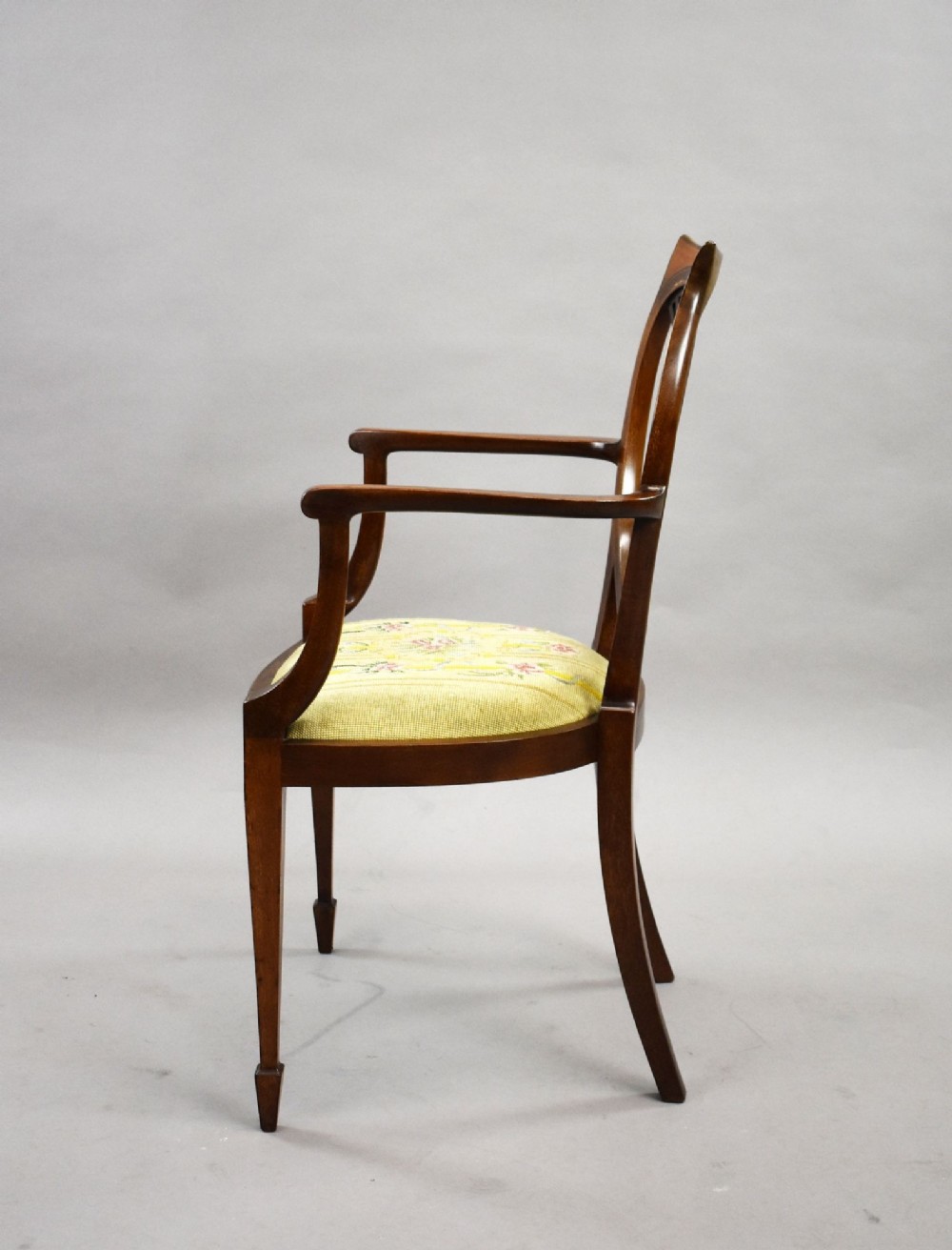 A pair of Edwardian Sheraton Revival mahogany armchairs featuring oval backs with vertical fan splats, swept arms, satinwood inlays, and yellow floral upholstered seats. View VI
