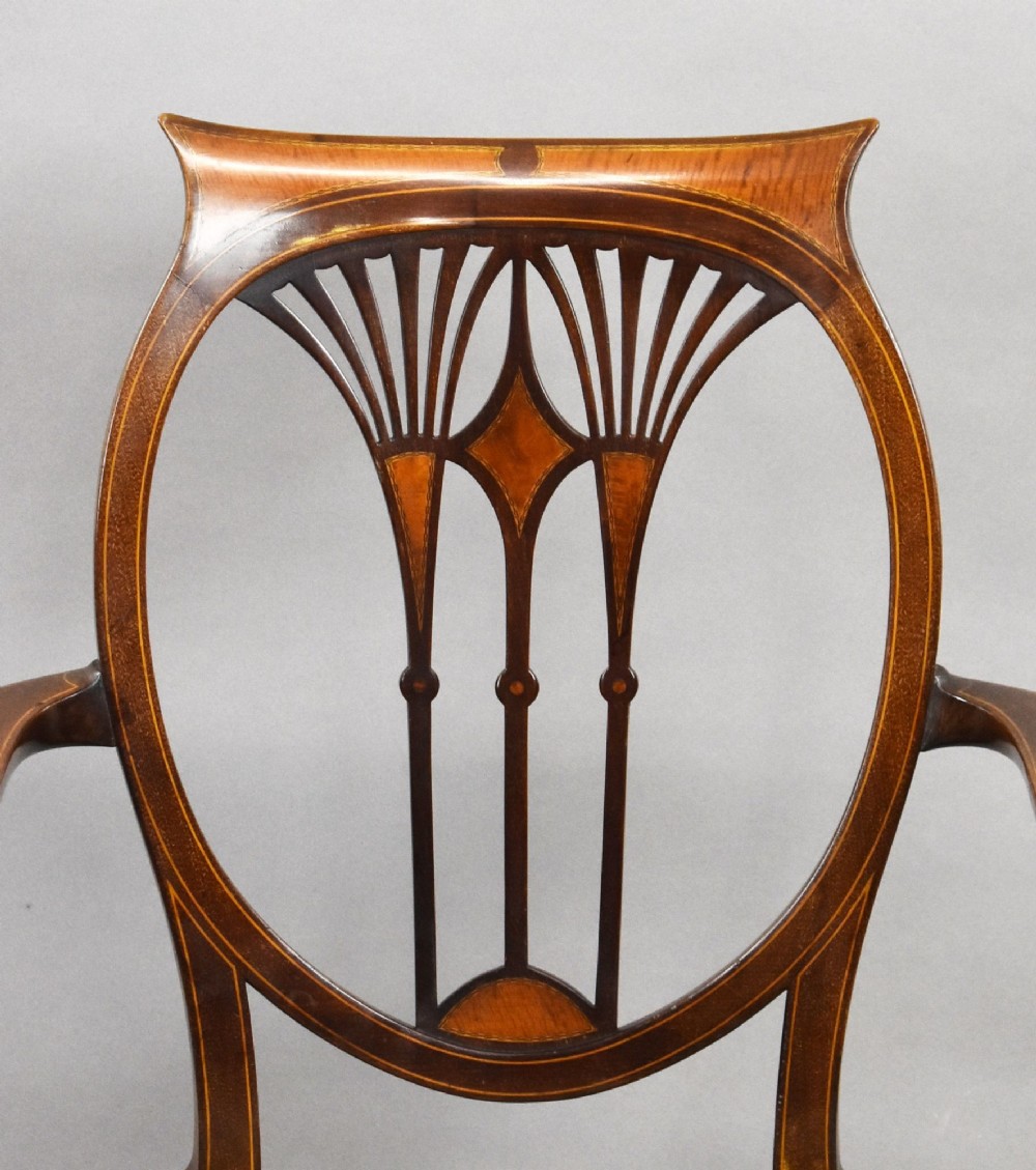 A pair of Edwardian Sheraton Revival mahogany armchairs featuring oval backs with vertical fan splats, swept arms, satinwood inlays, and yellow floral upholstered seats. View VII