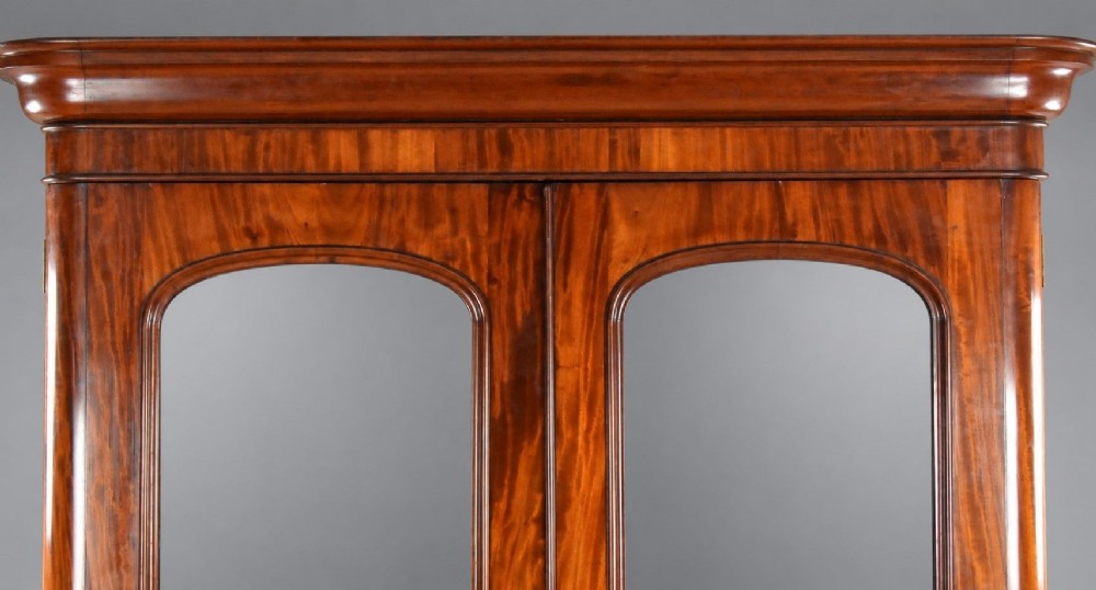 A nineteenth-century Victorian mahogany wardrobe featuring two arched mirrored doors above a single full-width drawer with turned wooden knobs. View V