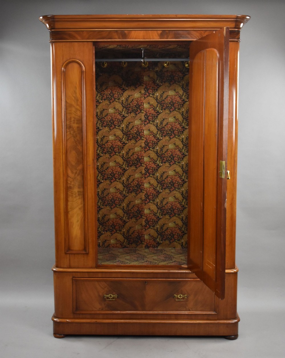 Victorian flame mahogany wardrobe featuring a central full-length arched mirror door flanked by arched wood panels, topped with a moulded cornice and resting on a base drawer. View II