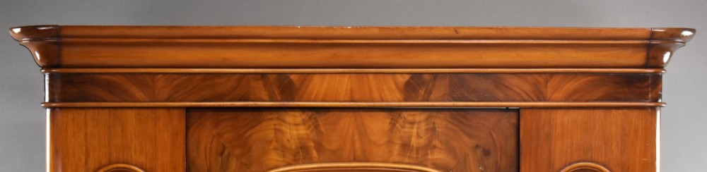 Victorian flame mahogany wardrobe featuring a central full-length arched mirror door flanked by arched wood panels, topped with a moulded cornice and resting on a base drawer. View III