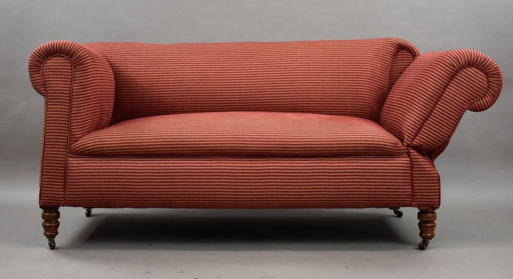 A late Victorian upholstered two-seater sofa featuring red striped fabric, scroll arms, and turned wooden legs with brass castors. View II