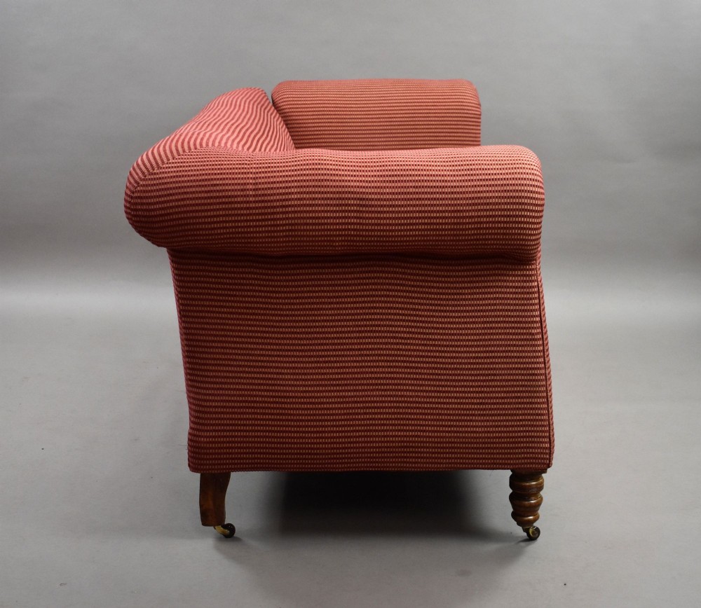 A late Victorian upholstered two-seater sofa featuring red striped fabric, scroll arms, and turned wooden legs with brass castors. View IV