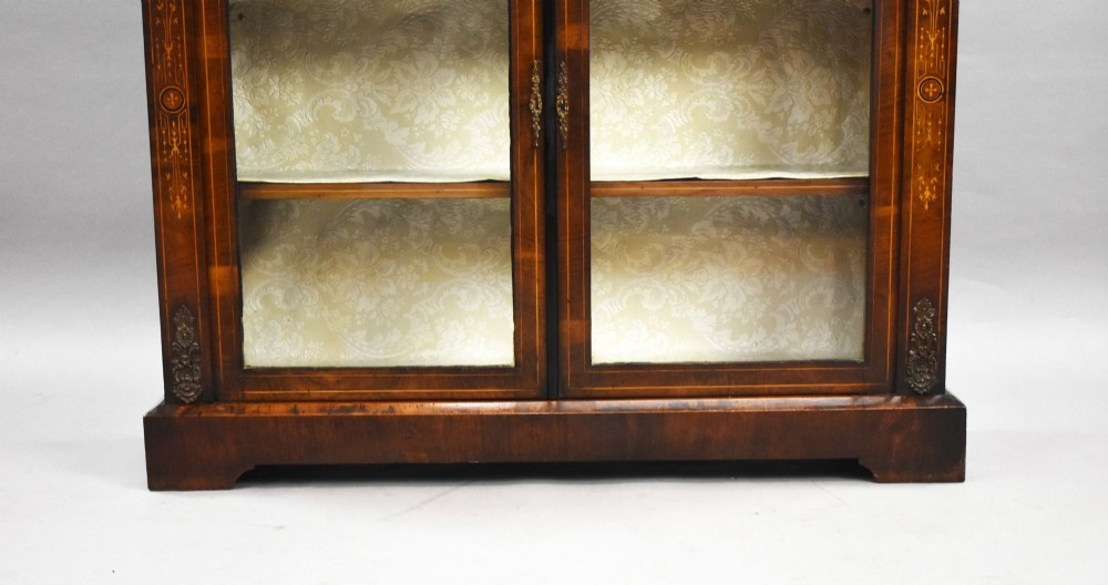 A Victorian mahogany pier cabinet featuring two glazed doors, floral marquetry inlay, gilt-bronze mounts, and a fabric-lined interior with shelves. View IV
