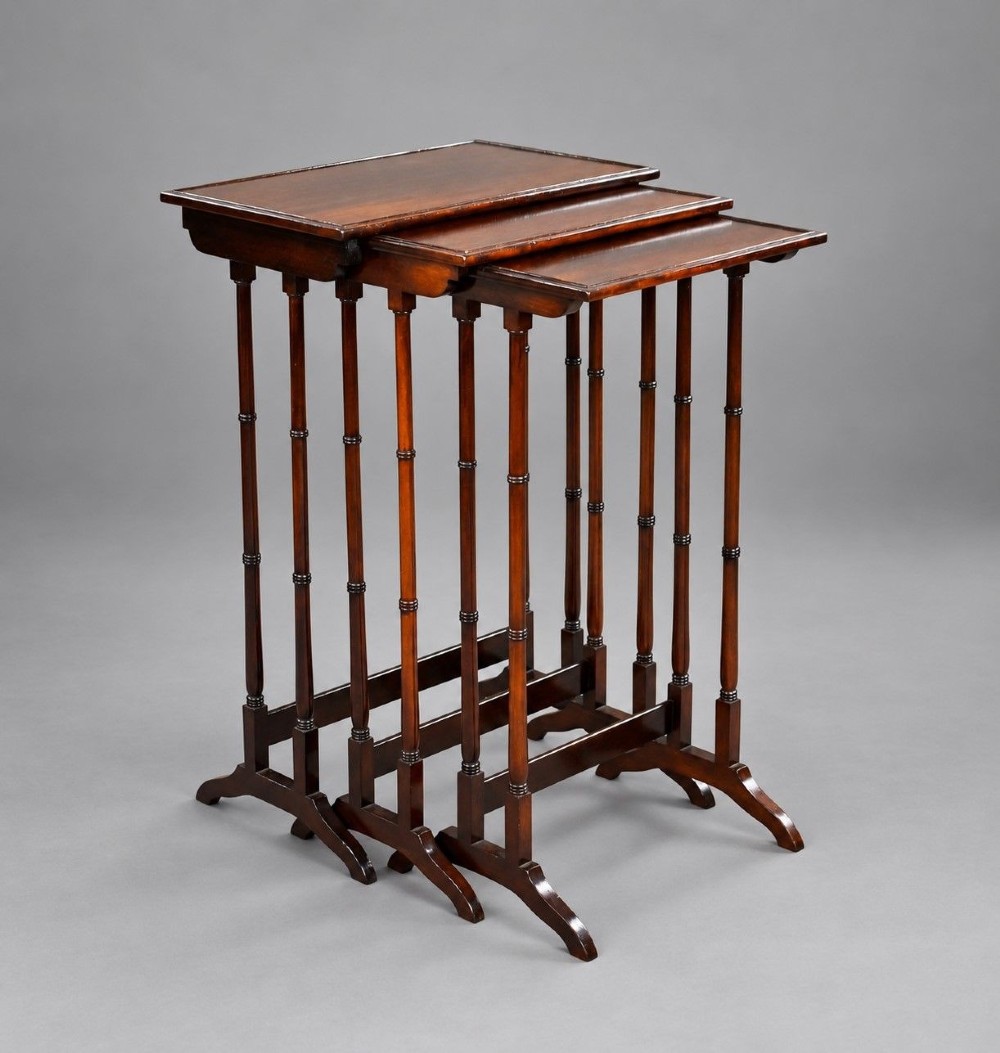 An Edwardian nest of three graduating mahogany tables with turned legs and trestle feet.
