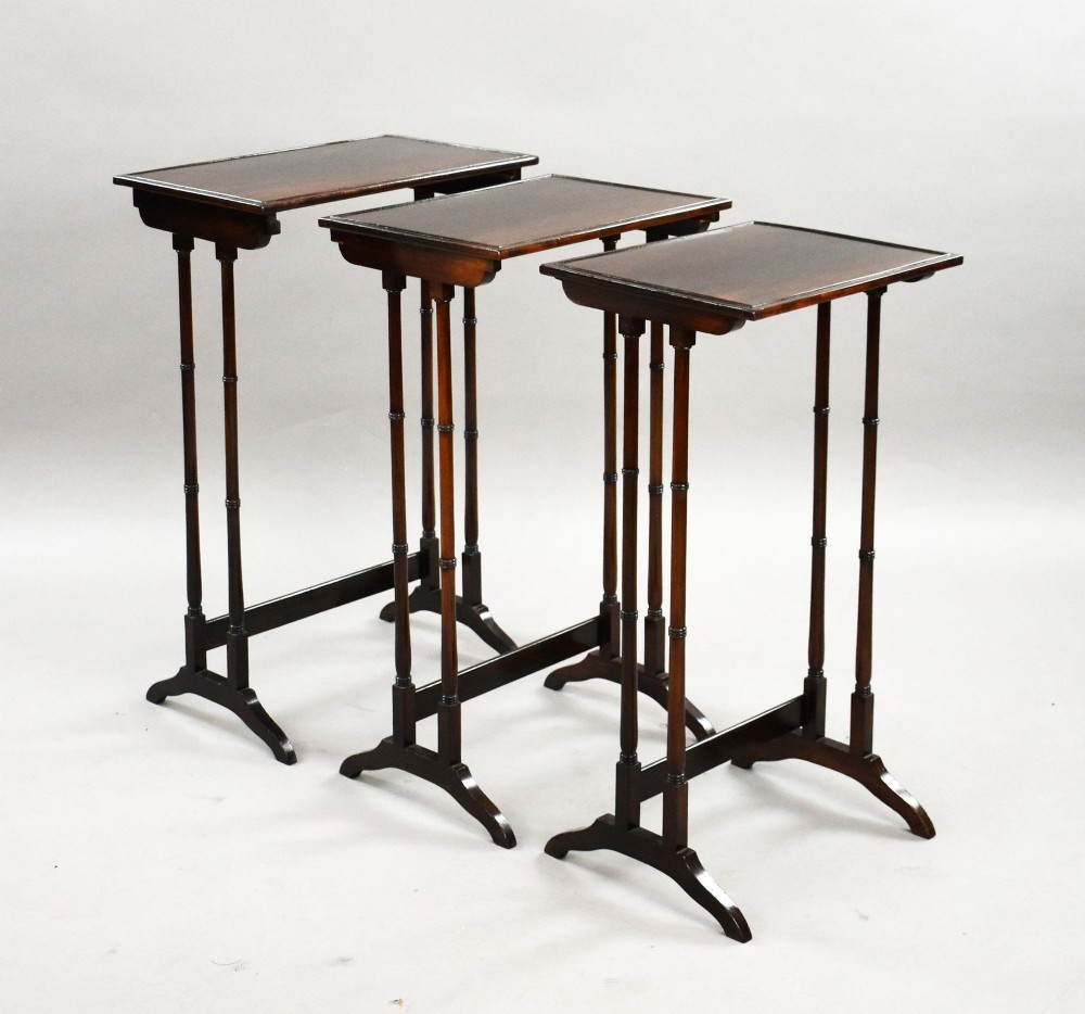 An Edwardian nest of three graduating mahogany tables with turned legs and trestle feet. View IV