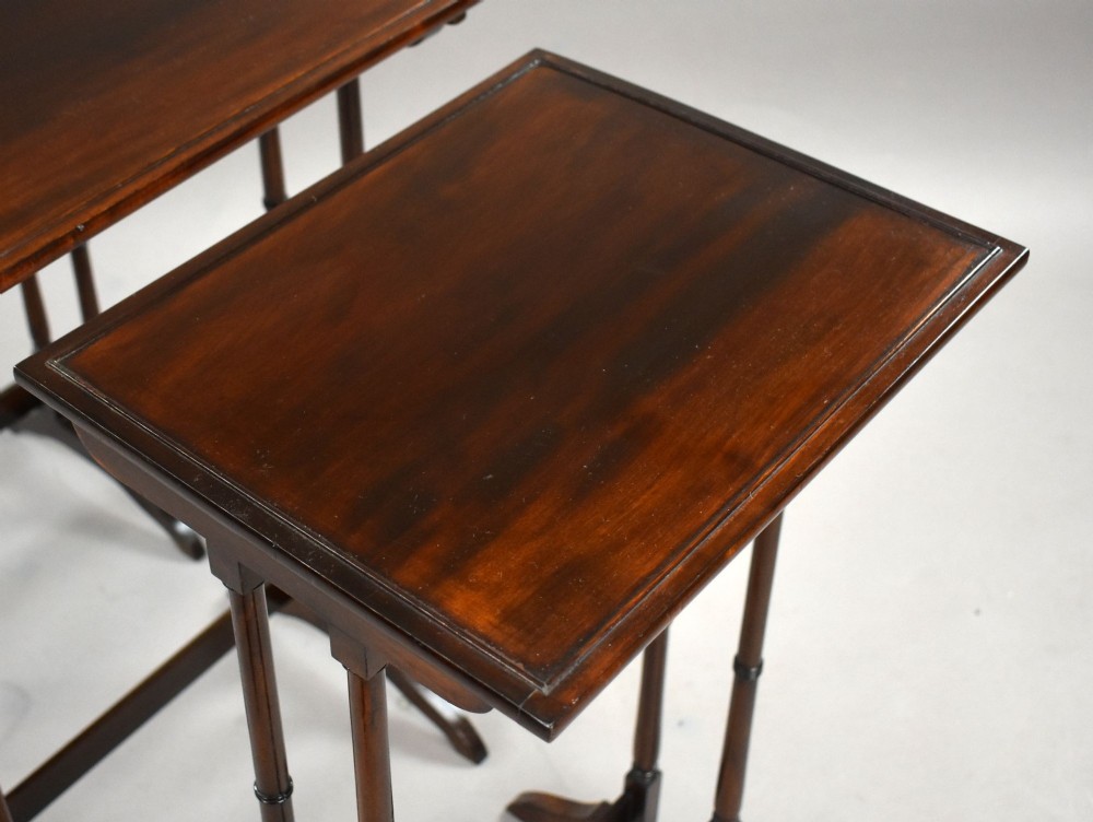 An Edwardian nest of three graduating mahogany tables with turned legs and trestle feet. View VII