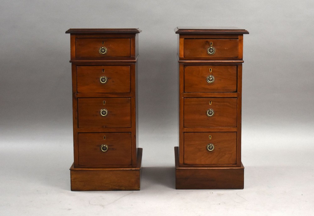 A matching pair of narrow Victorian mahogany bedside chests, each featuring four stacked drawers with central brass ring pulls set on a solid plinth base. View II