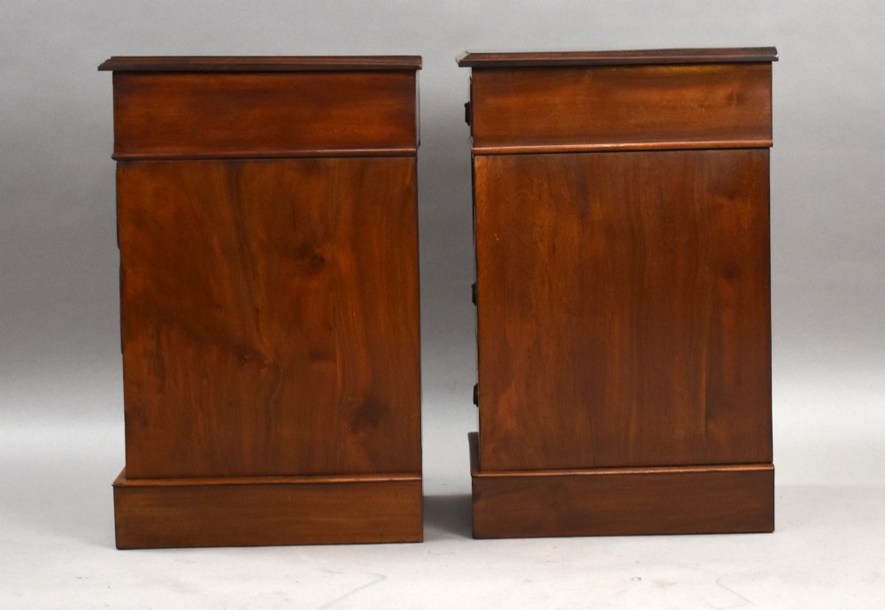 A matching pair of narrow Victorian mahogany bedside chests, each featuring four stacked drawers with central brass ring pulls set on a solid plinth base. View IV