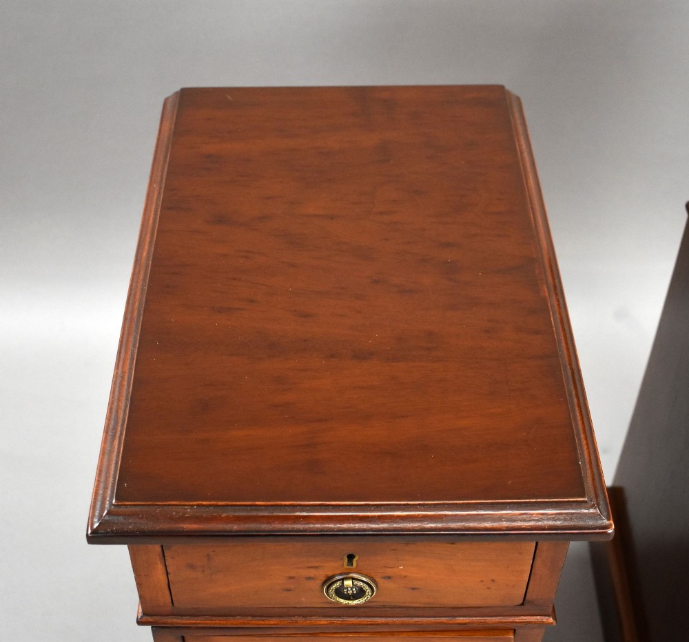 A matching pair of narrow Victorian mahogany bedside chests, each featuring four stacked drawers with central brass ring pulls set on a solid plinth base. View VII