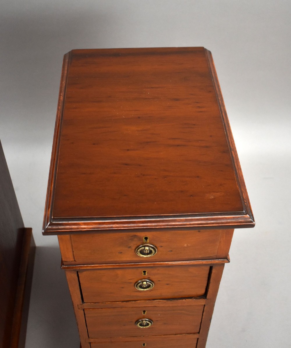 A matching pair of narrow Victorian mahogany bedside chests, each featuring four stacked drawers with central brass ring pulls set on a solid plinth base. View VIII