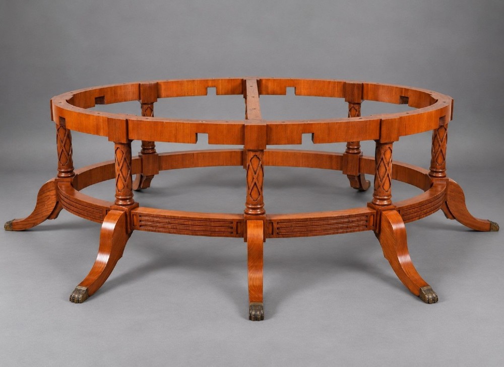 A large oval burr walnut extending dining table with inlaid crossbanding and pedestal legs terminating in brass castors. View IV