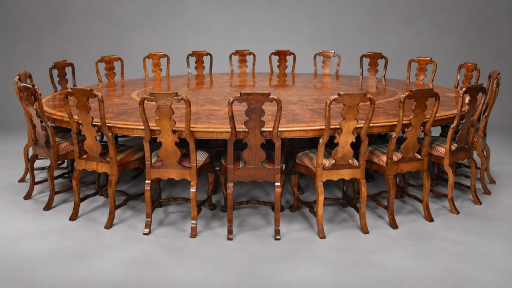A large oval burr walnut extending dining table with inlaid crossbanding and pedestal legs terminating in brass castors. View XI