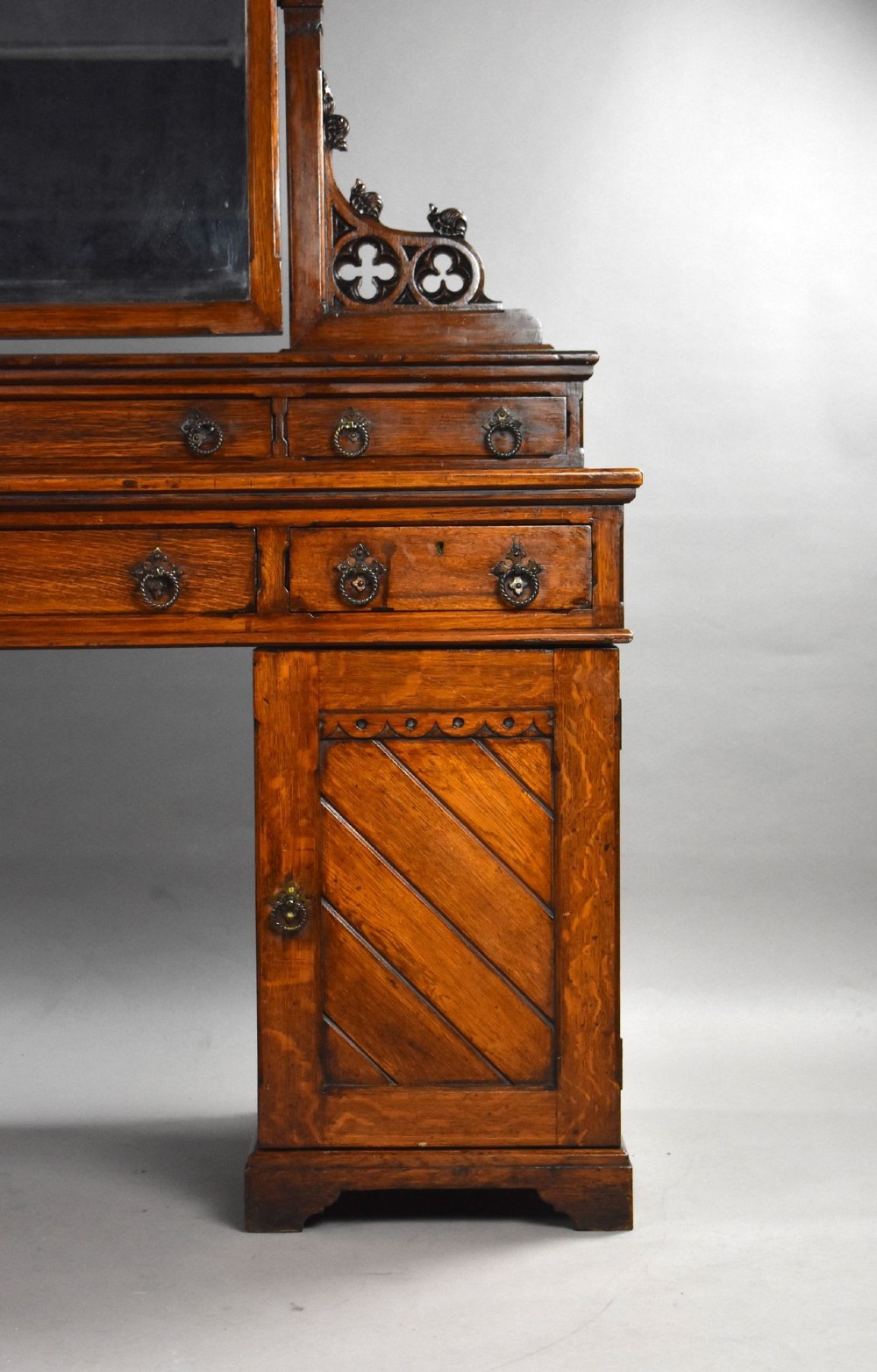 A Victorian Gothic Revival oak dressing table featuring a central pointed arched mirror, trefoil tracery carvings, multiple drawers, and pedestal cupboards with diagonal wood panelling. View III