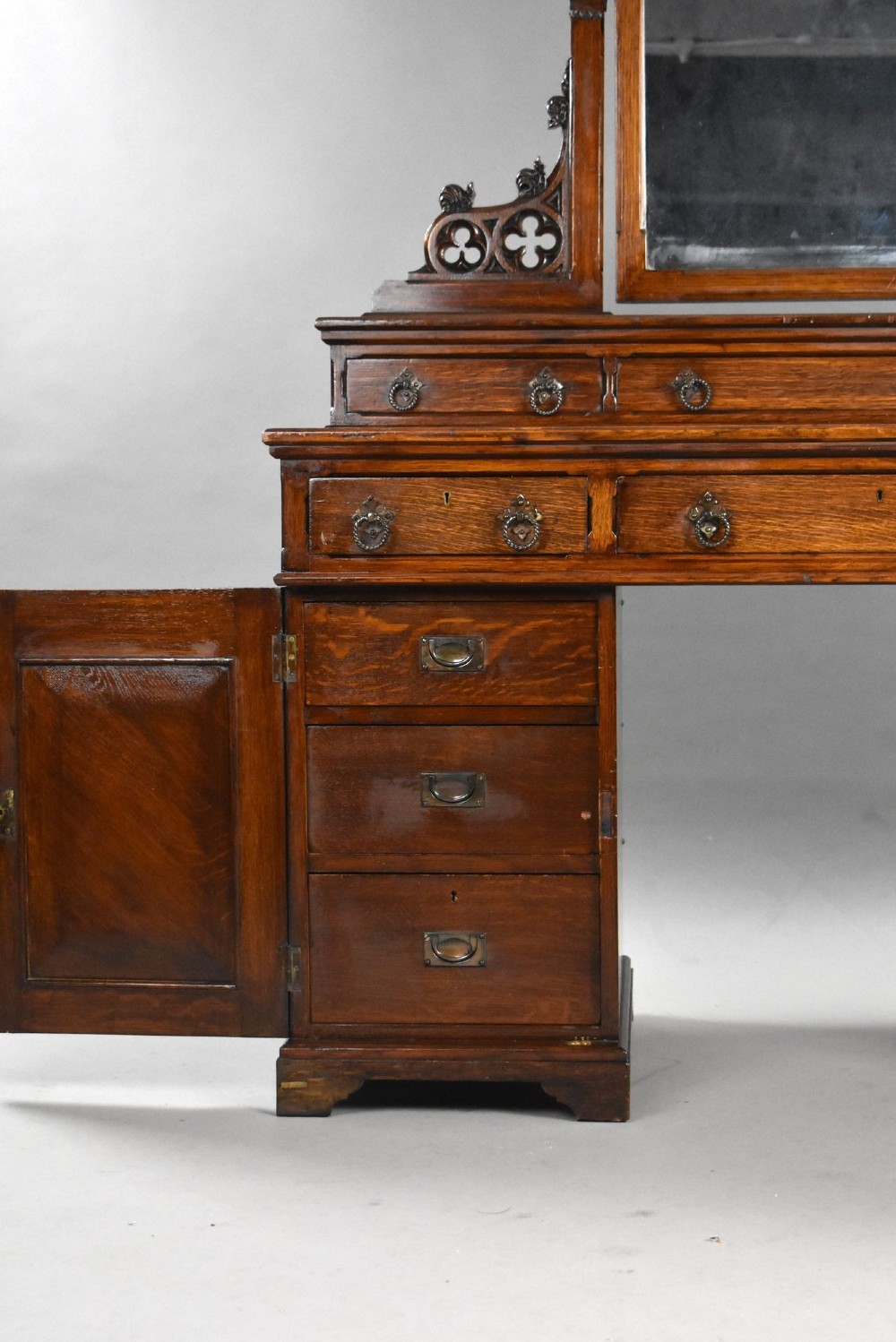 A Victorian Gothic Revival oak dressing table featuring a central pointed arched mirror, trefoil tracery carvings, multiple drawers, and pedestal cupboards with diagonal wood panelling. View V