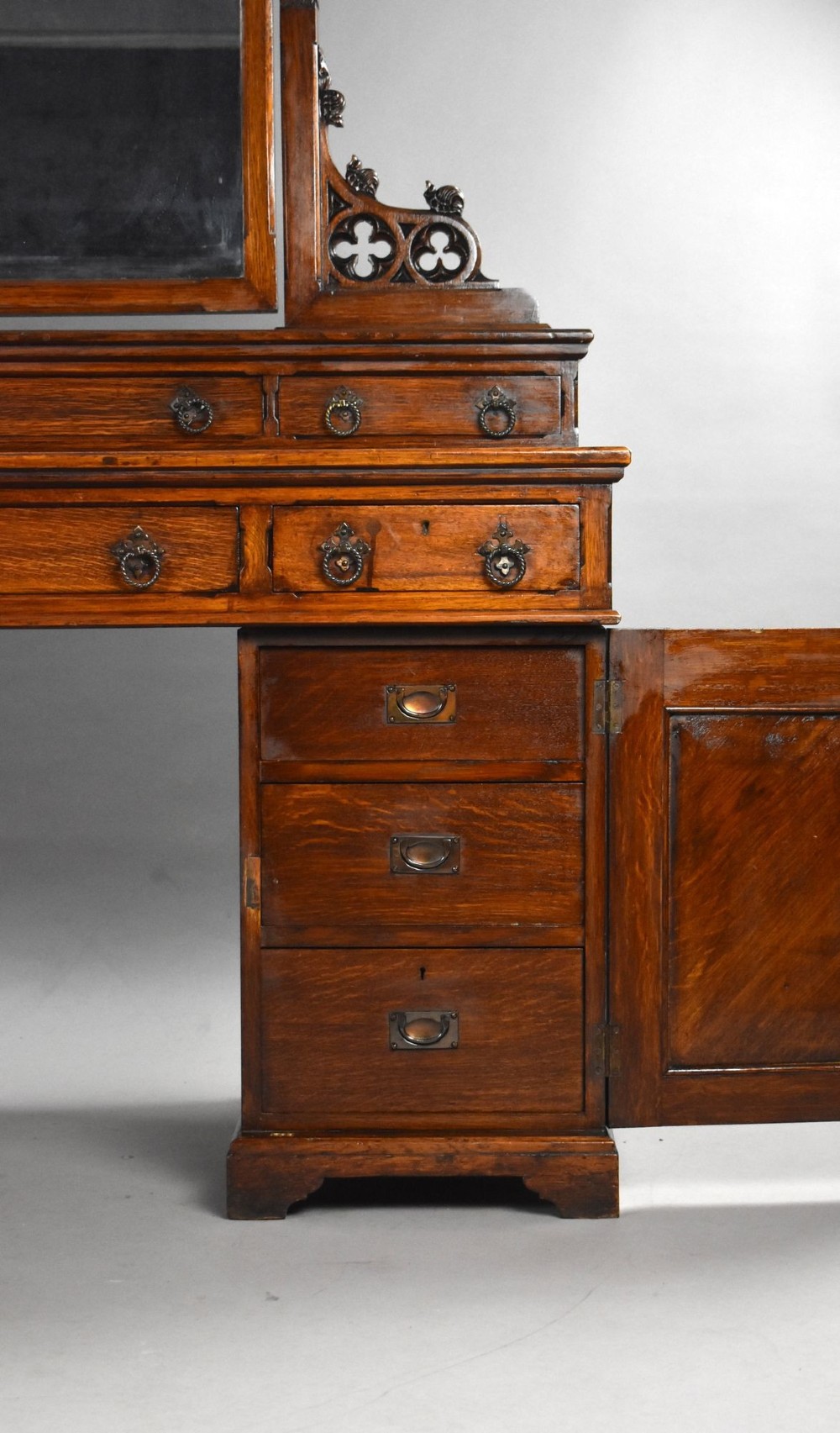 A Victorian Gothic Revival oak dressing table featuring a central pointed arched mirror, trefoil tracery carvings, multiple drawers, and pedestal cupboards with diagonal wood panelling. View VI