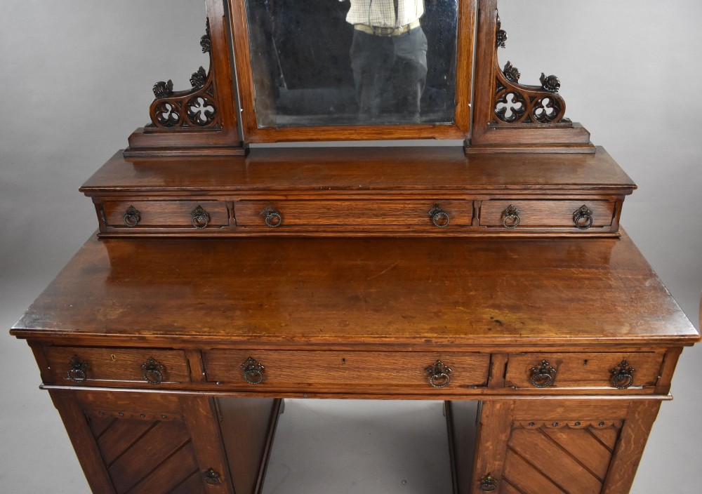 A Victorian Gothic Revival oak dressing table featuring a central pointed arched mirror, trefoil tracery carvings, multiple drawers, and pedestal cupboards with diagonal wood panelling. View VII