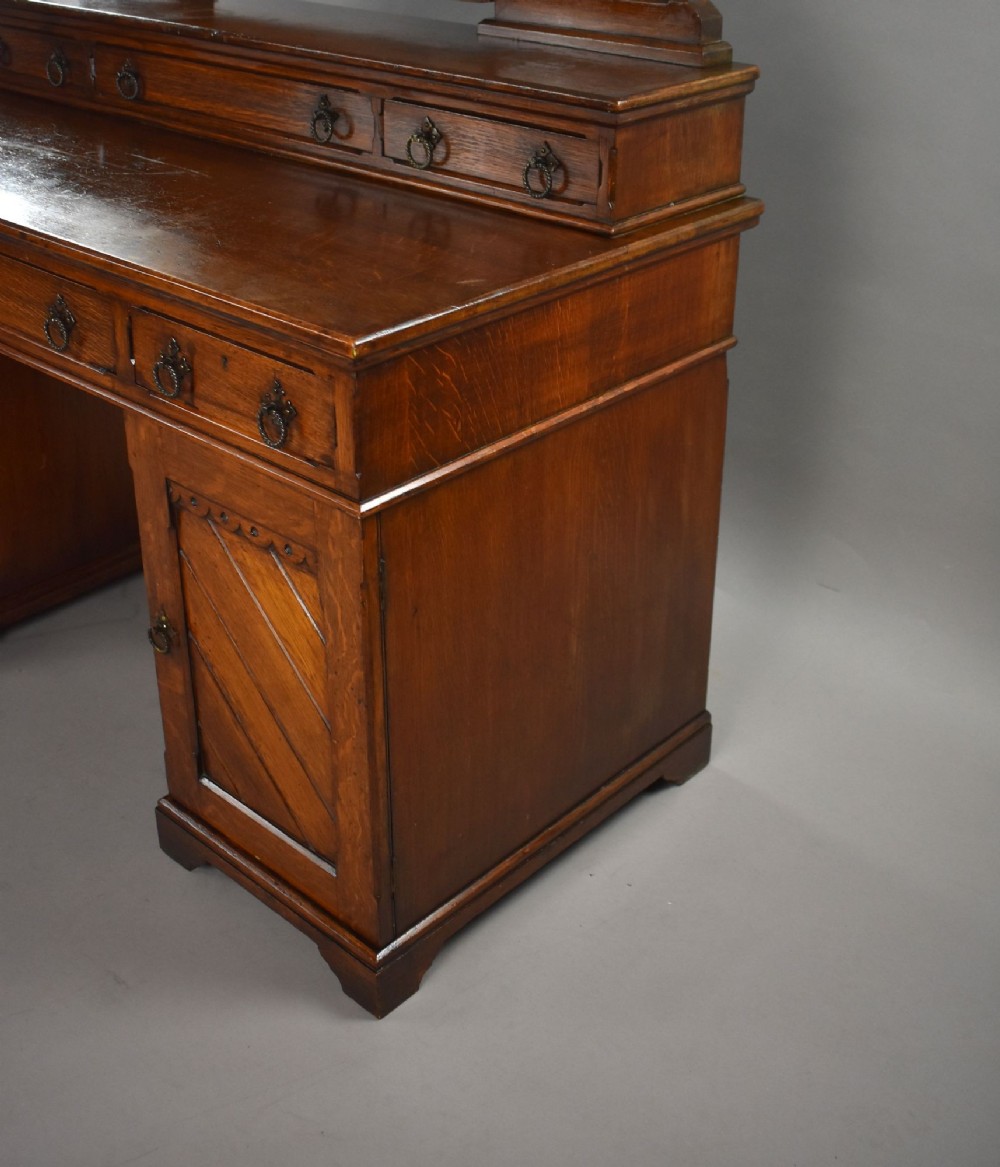A Victorian Gothic Revival oak dressing table featuring a central pointed arched mirror, trefoil tracery carvings, multiple drawers, and pedestal cupboards with diagonal wood panelling. View IX