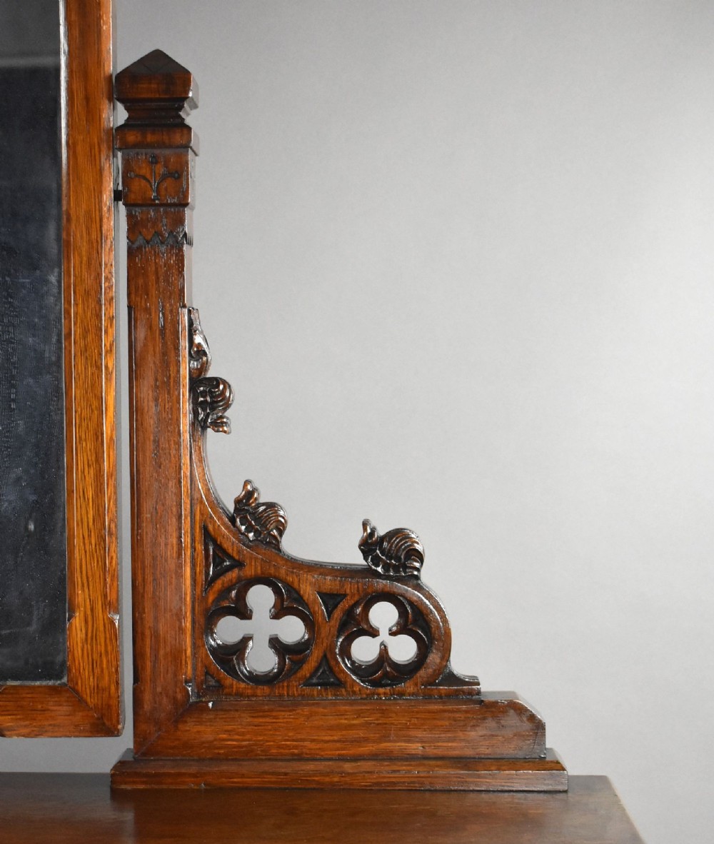 A Victorian Gothic Revival oak dressing table featuring a central pointed arched mirror, trefoil tracery carvings, multiple drawers, and pedestal cupboards with diagonal wood panelling. View XI