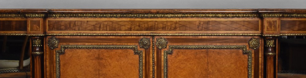 A Victorian burr walnut credenza featuring central cupboard doors with oval porcelain plaques and gilt bronze mounts flanked by curved open display shelves. View VIII