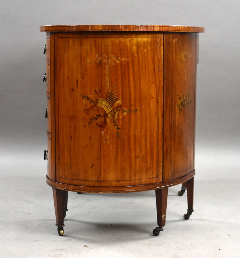 An Edwardian satinwood kidney-shaped writing desk featuring nine hand-painted drawers with brass ring handles and tapered legs on castors. View V
