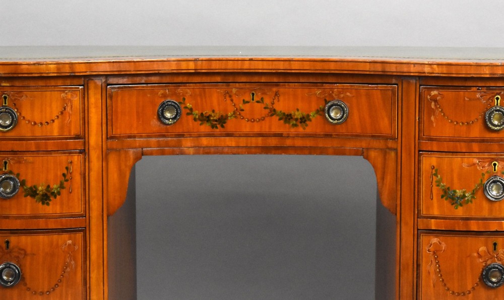 An Edwardian satinwood kidney-shaped writing desk featuring nine hand-painted drawers with brass ring handles and tapered legs on castors. View VIII