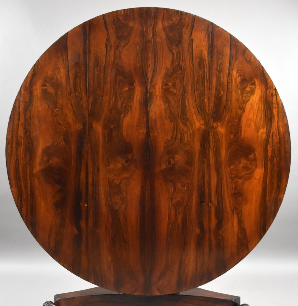 A William IV circular rosewood tilt-top breakfast table showing a book-matched grain pattern displayed vertically above a triform base. View II