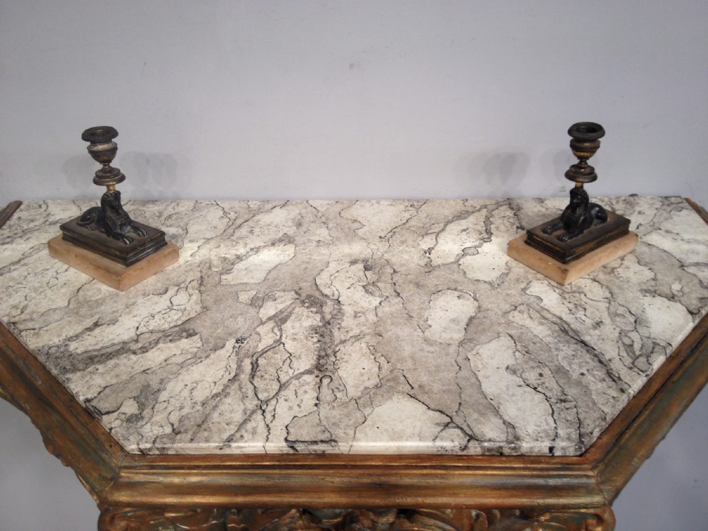 An antique carved giltwood console table featuring a single caryatid monopodium leg, scrollwork apron, and a white veined marble top. View III