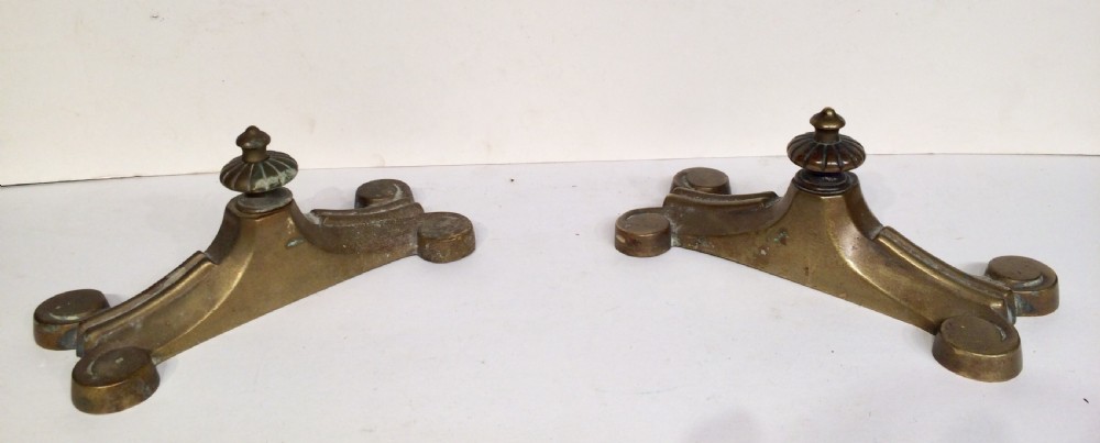 A pair of heavy Victorian cast brass doorstops with flared scroll feet and fluted central finials showing aged patina.