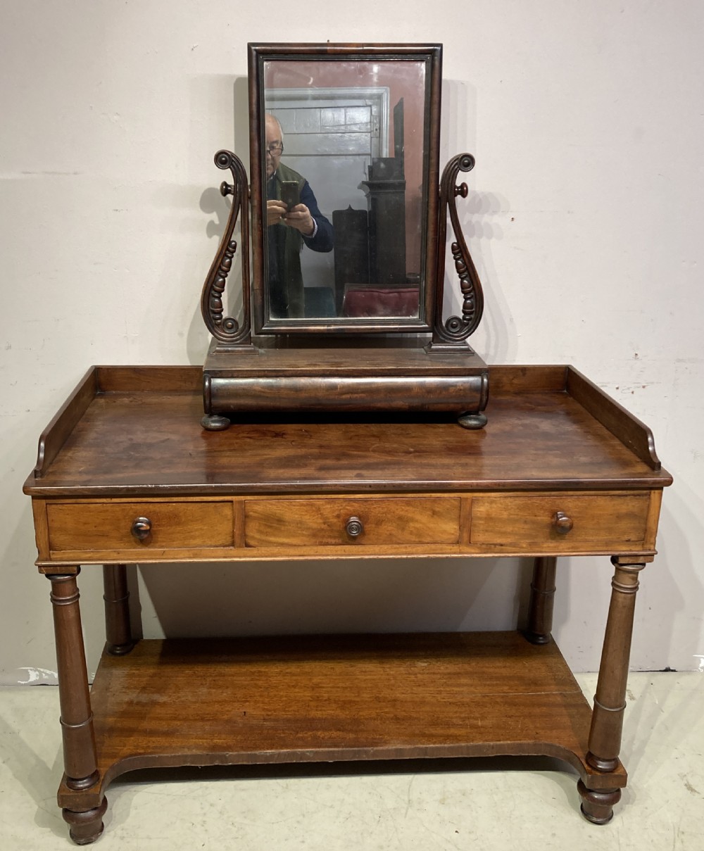 A William IV mahogany dressing table featuring a low gallery back, three frieze drawers with wooden knobs, turned legs, and a fitted lower undertier shelf. View V