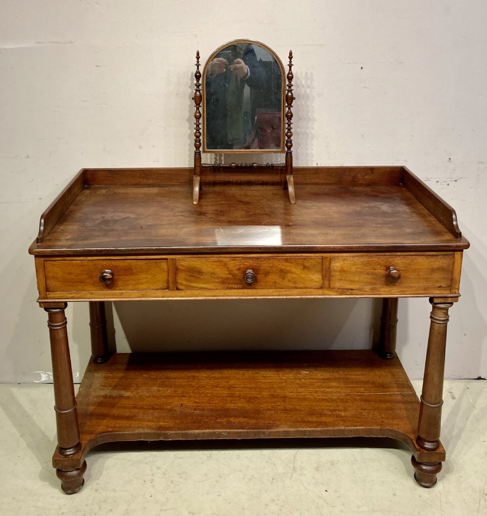 A William IV mahogany dressing table featuring a low gallery back, three frieze drawers with wooden knobs, turned legs, and a fitted lower undertier shelf. View VI