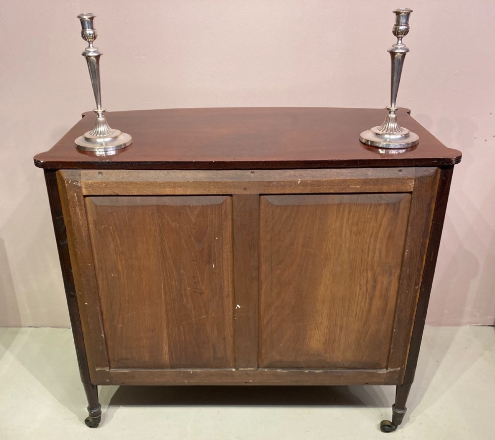 A Regency period warm brown mahogany bow-fronted chest of drawers featuring eight drawers with brass lion-head ring pulls, reeded side pilasters, and turned legs on castors. View VII