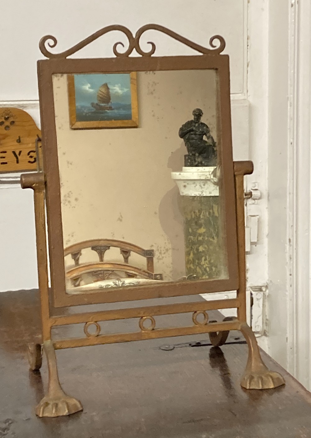 A rectangular gilded metal dressing table mirror featuring a scrolled crest, swivel frame, and splayed paw feet with foxed glass. View V