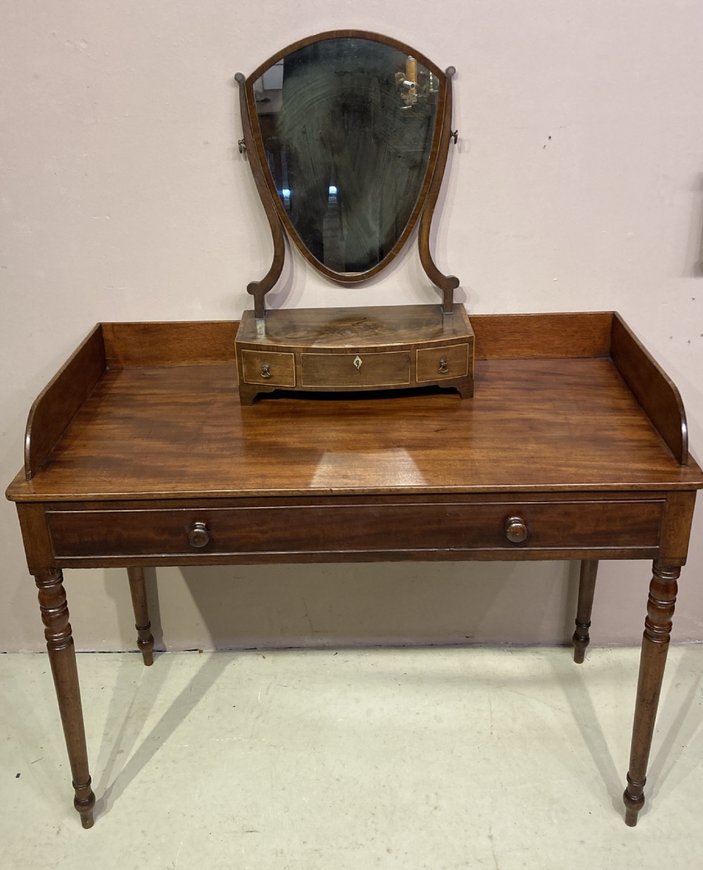 A freestanding antique Georgian mahogany writing desk featuring a raised gallery back, two drawers with turned wooden knobs, and turned tapering legs. View IX