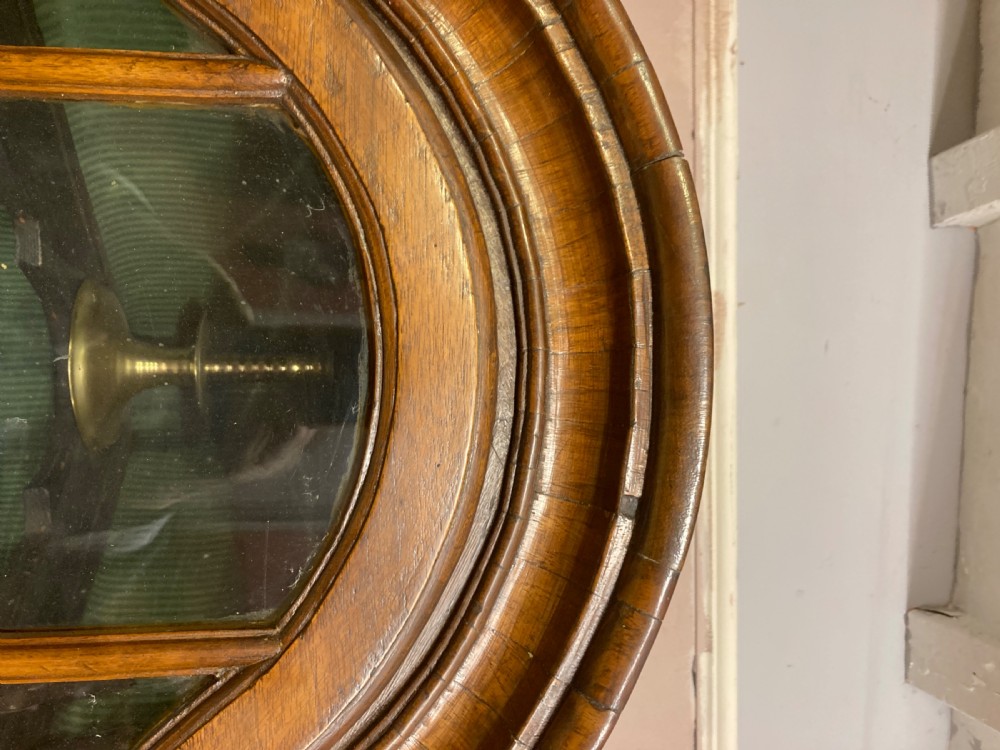 A tall antique walnut corner cabinet featuring an arched glazed upper door, a central drawer, and inlaid double doors below. View IV