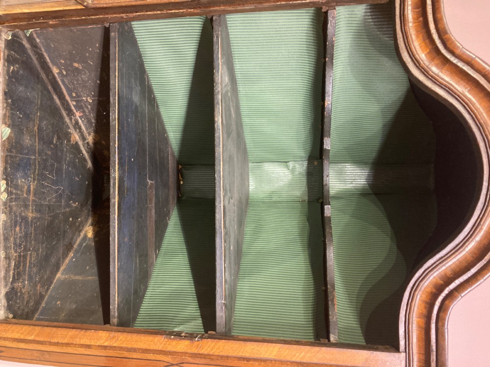 A tall antique walnut corner cabinet featuring an arched glazed upper door, a central drawer, and inlaid double doors below. View VII