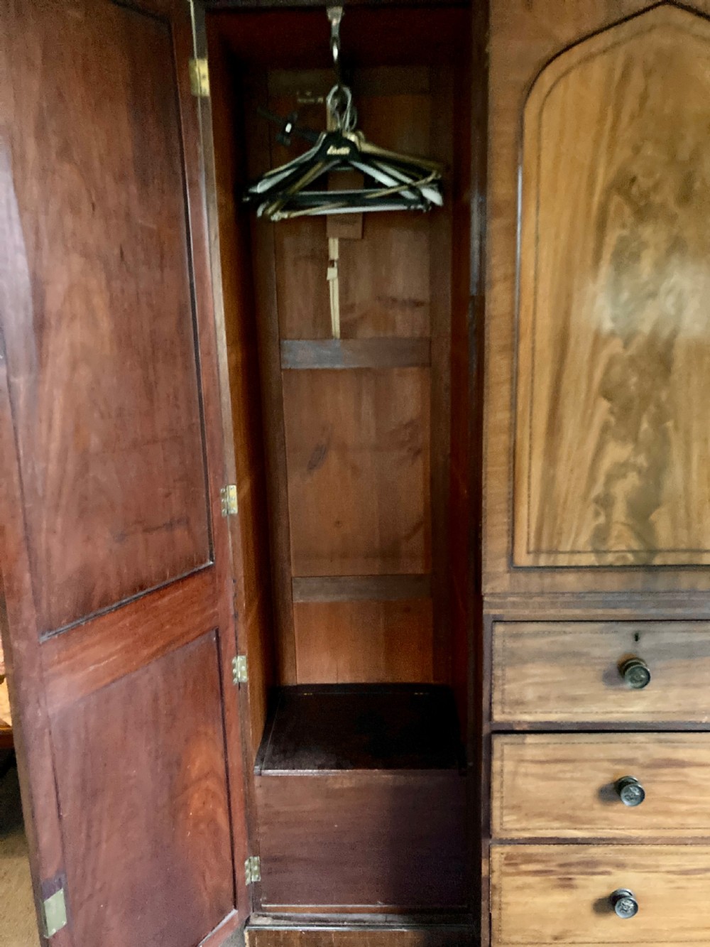 A large Georgian mahogany breakfront wardrobe featuring flame mahogany doors with pointed arch panels above a central chest of drawers. View IX
