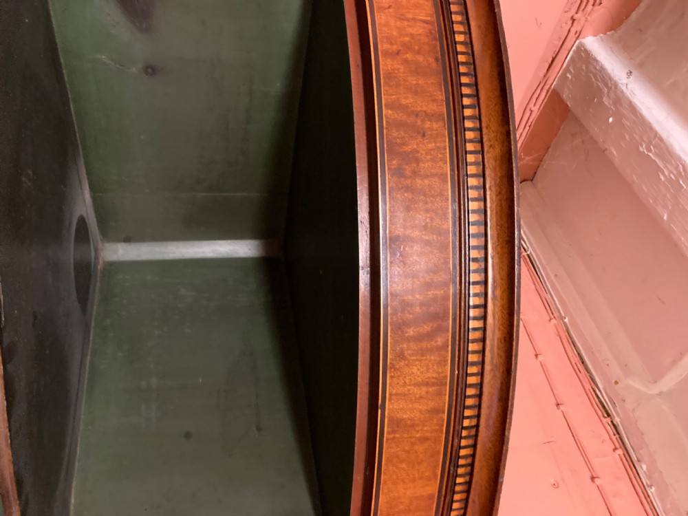 A Georgian mahogany bowfront hanging corner cupboard featuring double panelled doors, boxwood inlay, and brass escutcheons. View IV