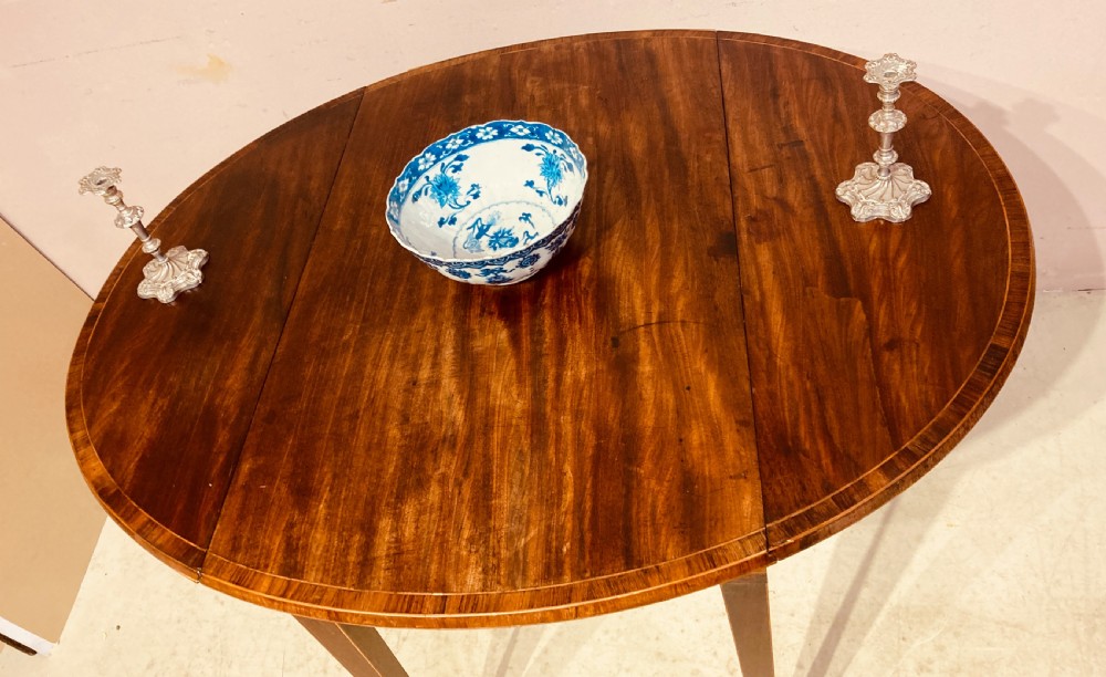 A Georgian mahogany oval Pembroke table featuring extended drop leaves, fine string inlay, a single drawer with brass ring handles, and square tapered legs. View III