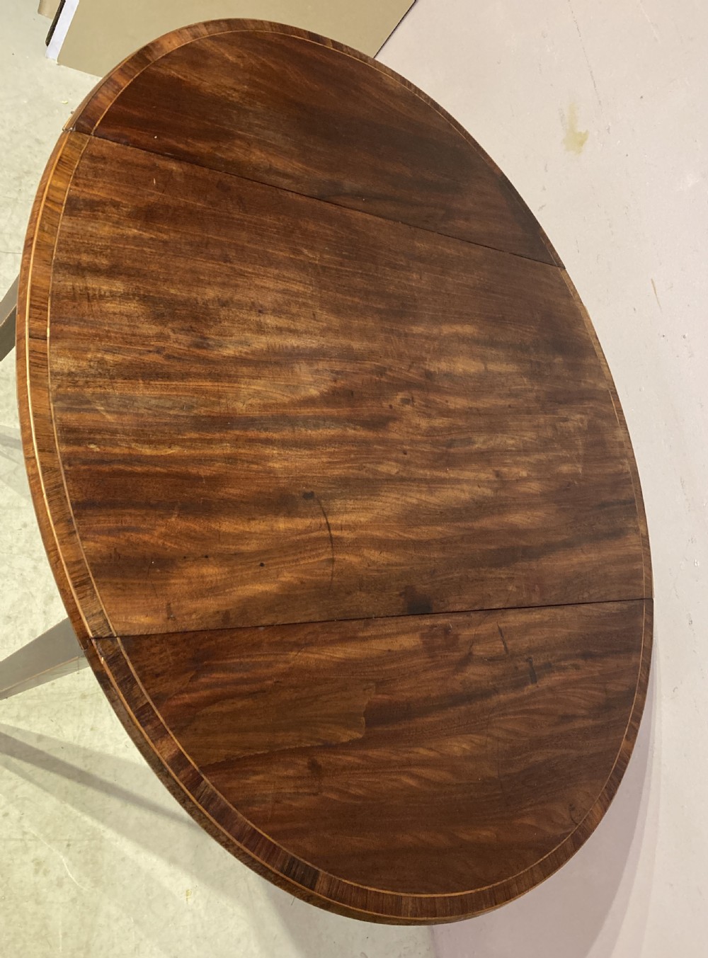 A Georgian mahogany oval Pembroke table featuring extended drop leaves, fine string inlay, a single drawer with brass ring handles, and square tapered legs. View IV