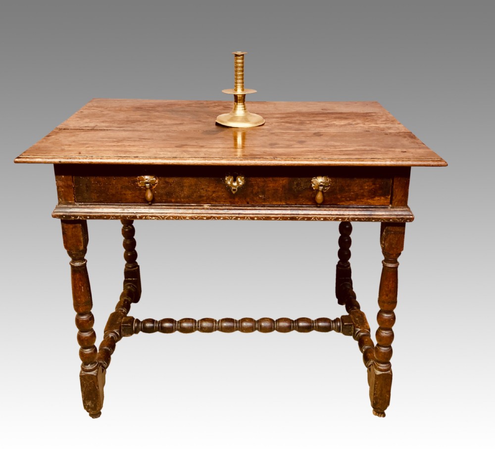 An 18th-century oak and elm side table featuring a single drawer with brass handles, turned legs, and a bobbin stretcher.