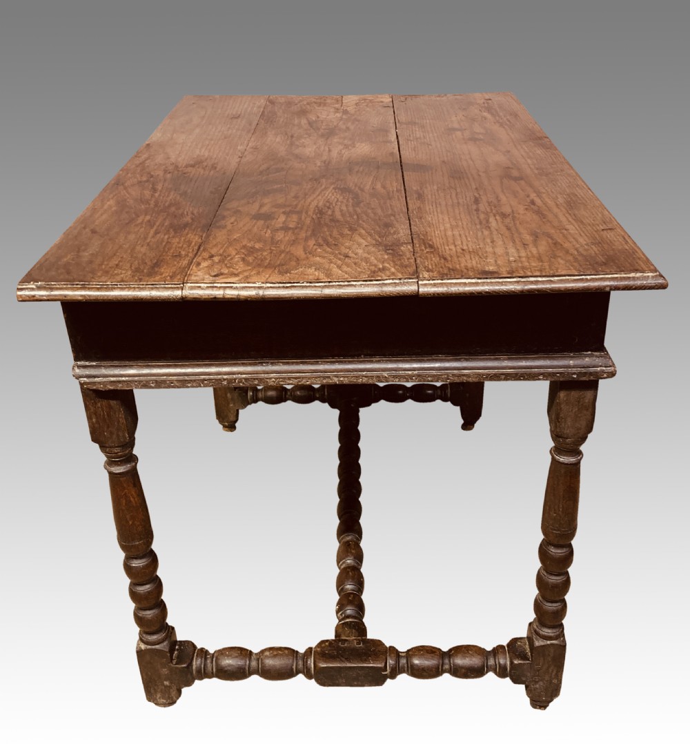 An 18th-century oak and elm side table featuring a single drawer with brass handles, turned legs, and a bobbin stretcher. View X