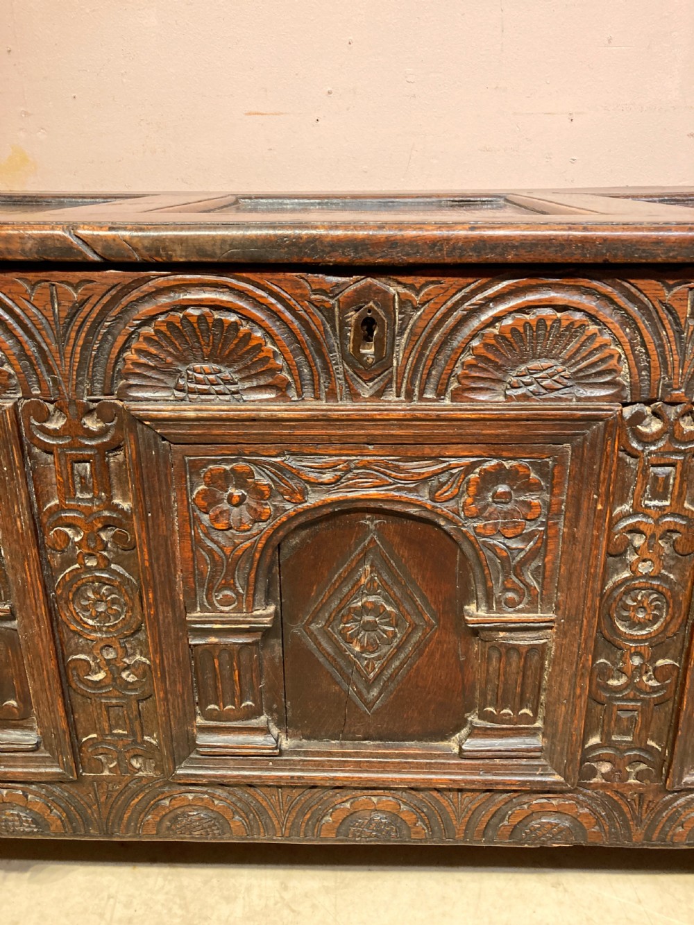 A 17th-century dark carved oak coffer featuring three arcaded front panels decorated with geometric motifs and lunette carving. View II