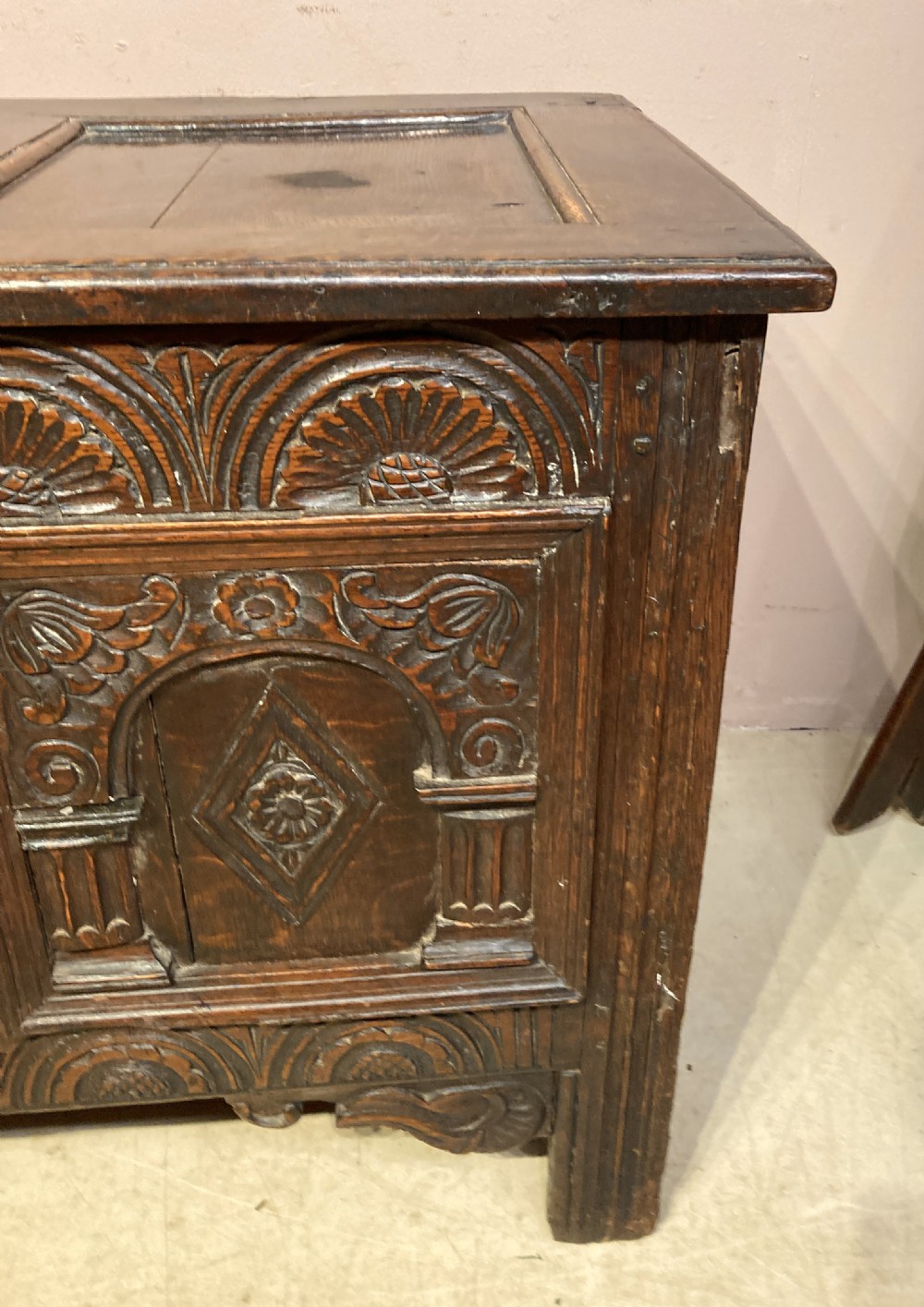 A 17th-century dark carved oak coffer featuring three arcaded front panels decorated with geometric motifs and lunette carving. View V