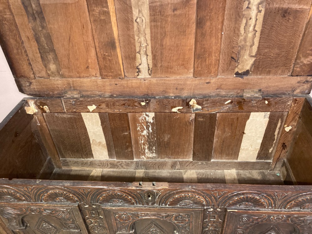 A 17th-century dark carved oak coffer featuring three arcaded front panels decorated with geometric motifs and lunette carving. View VI