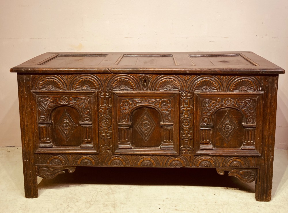 A 17th-century dark carved oak coffer featuring three arcaded front panels decorated with geometric motifs and lunette carving. View XI