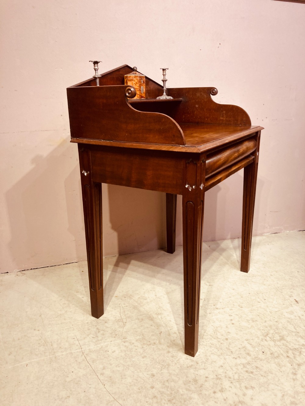 A Georgian mahogany writing table featuring a shaped gallery back shelf, a rounded tamboured front section, and square tapered legs. View VII