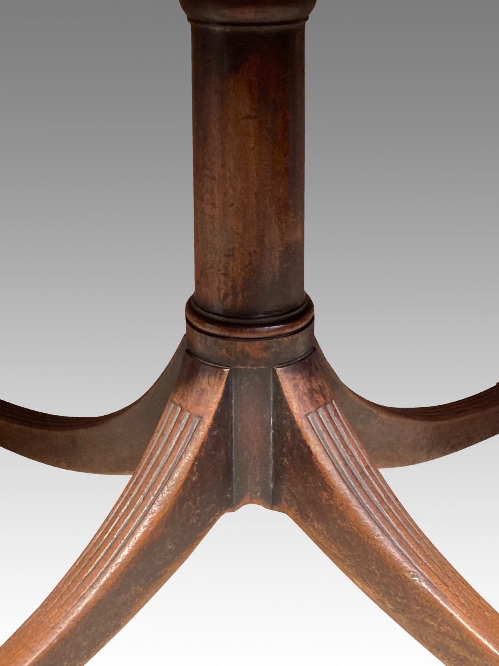 A Georgian mahogany dining table featuring a polished rectangular top with rounded corners supported by two central turned pedestals with splayed reeded legs ending in brass castors. View III